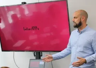 un hombre junto a una pantalla dando una formación