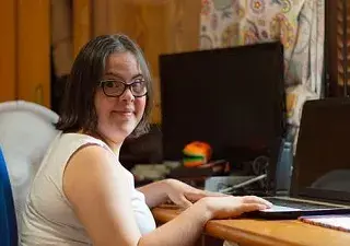 Joven con Síndrome de Down estudiando con su pórtatil