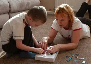 Los juguetes que aconsejan regalar para estas navidades a los niños con TEA, son aquellos que ayuden a su desarrollo en general, como esta madre con su hijo intentando hacer un puzzle (Fuente: El Plural)