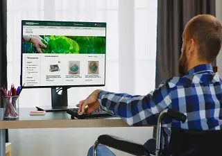 Un hombre usuario de silla de ruedas navega por la nueva página web de compra online de Eroski