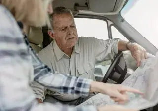 pareja de tercera edad mirando un mapa antes de conducir