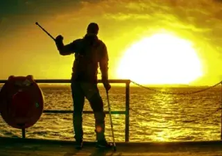 Una persona con discapacidad mirando al mar en una zona costera (Fuente: Cocemfe)