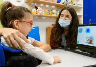 Una niña con discapacidad con un juguete adaptado y su tutora al lado (Fuente: Irisbond)