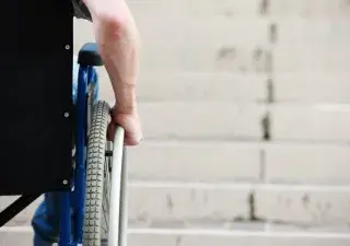 silla de ruedas vista desde la espalda con unas escaleras de fondo