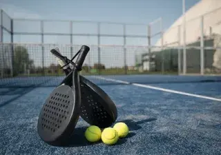 raquetas de padel de pies, junto a pelotas y al fondo la pista de padel