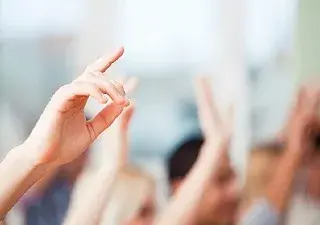 Personas con las manos en alto señalando algo